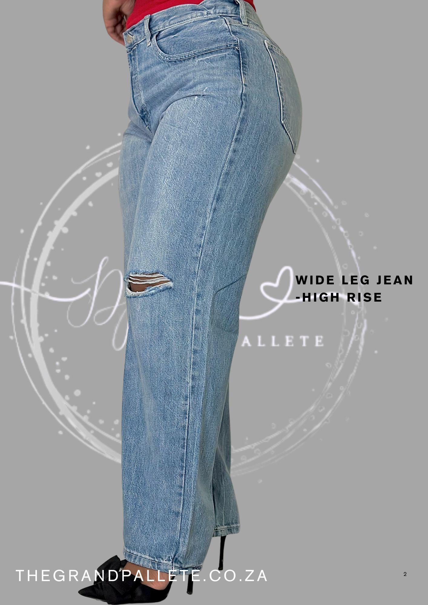 Blue wide-leg jeans with a slight tear on a gray background